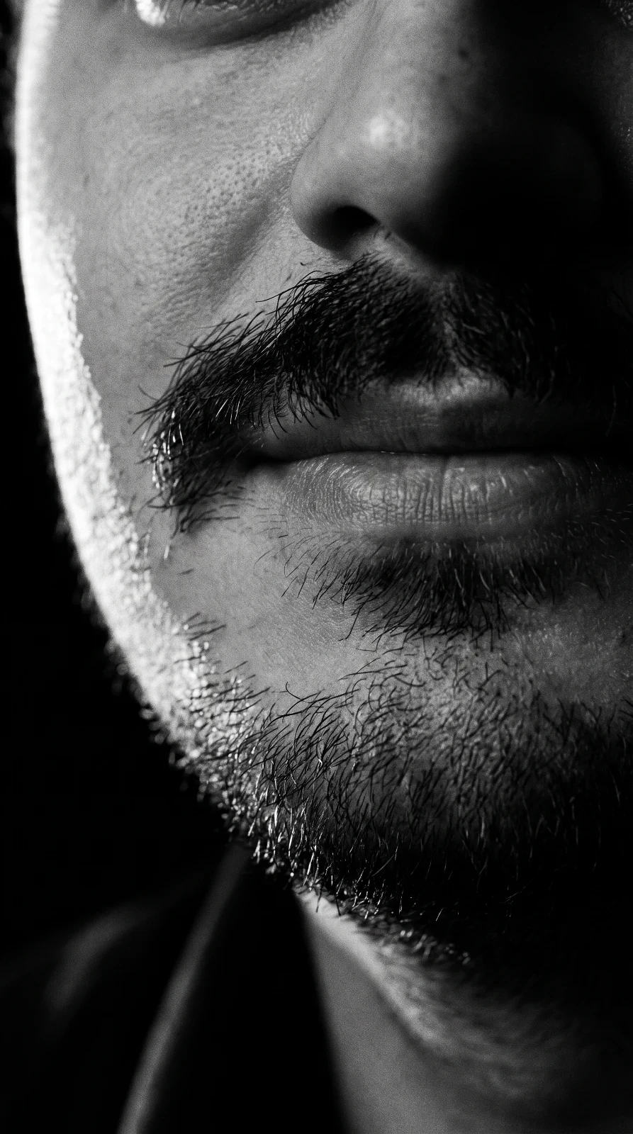 Close do rosto do investigador, com bigode e luz lateral.